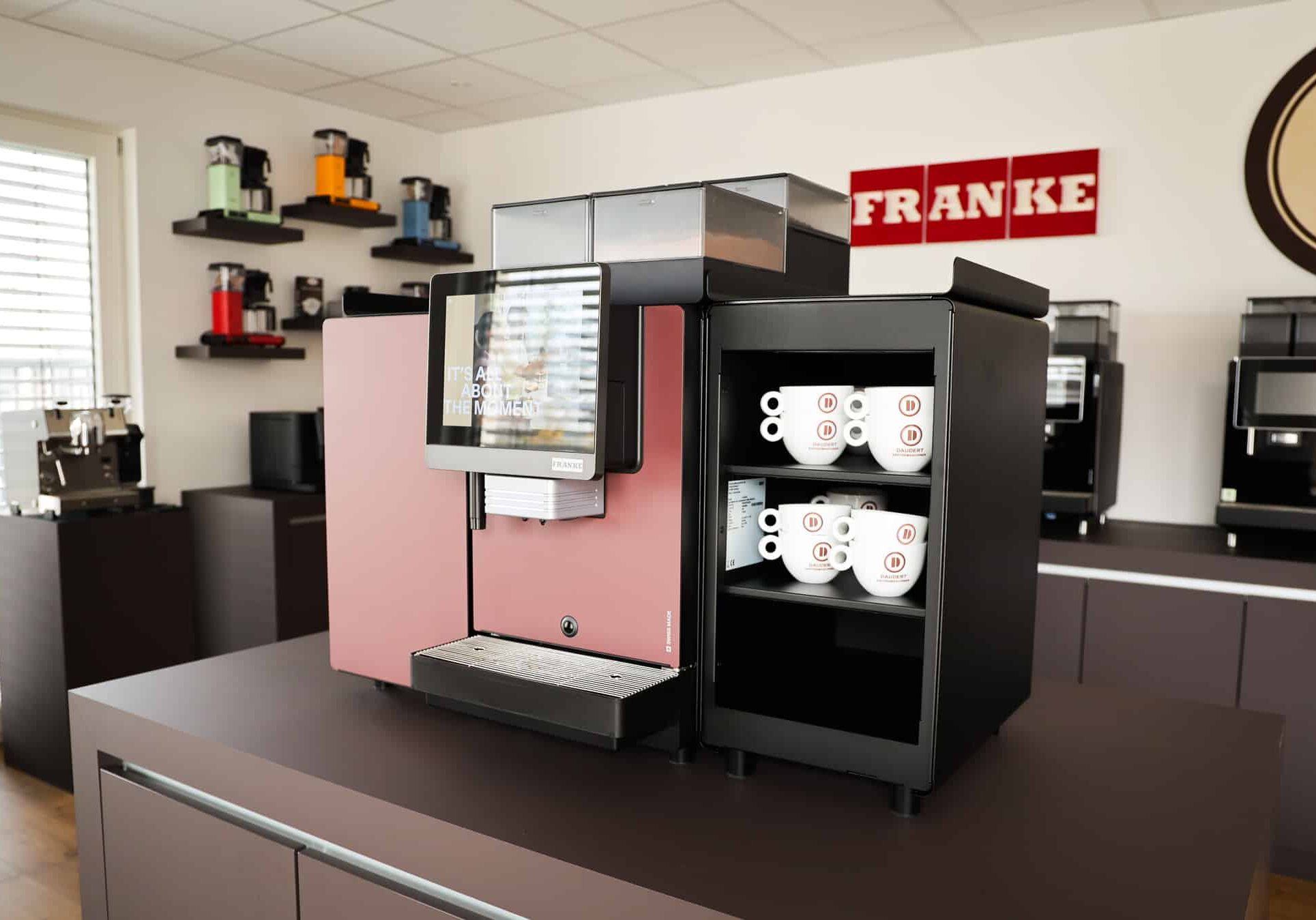 Franke Kaffeevollautomat mit Display und Daudert Kaffeetassen im Regal im Showroom